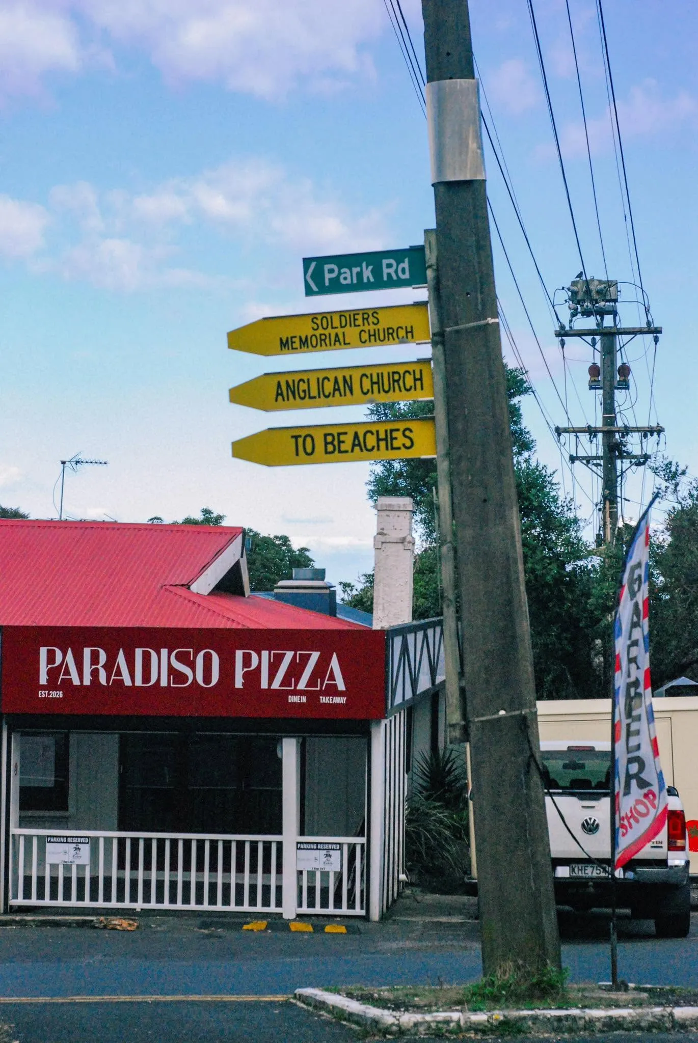 Paradiso Pizza storefront below the Park Road street sign