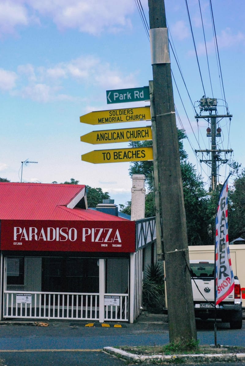 Paradiso Pizza storefront below the Park Road street sign